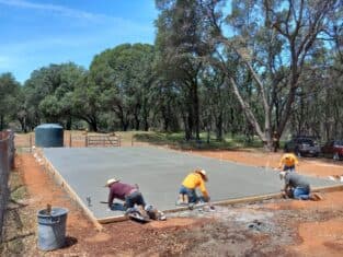 Foundation of the construction of a new home and the contractors smoothing out the cemement and taking measurements.