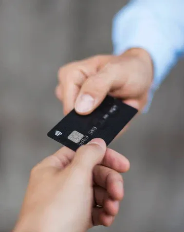 Two hands exchanging a black credit card, depicting a financial transaction, evokes the seamless efficiency of a remodeling project's final stages.